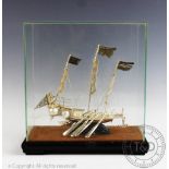 An early 20th century white metal Junk modelled in full sail within a glazed display case,