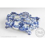 A 19th century continental blue and white faience inkwell, of Rococo style, on scroll legs,
