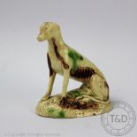 An 18th century Whieldon type creamware model of a seated dog,
