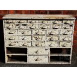 A late Victorian white painted pine apothecary type bank of drawers,