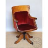 An Edwardian oak swivel desk chair, of vintage stye, with red upholstery and scroll end arms,