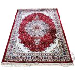 A Kashmir rug, worked with a central medallion against a floral red ground,