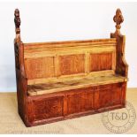 A carved oak hall settle converted from a pew,
