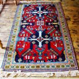 An Azerbaijan wool rug, worked with geometric motifs against a red ground,