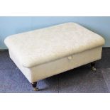 A modern ottoman, with floral pale green upholstery, on turned legs with brass casters,