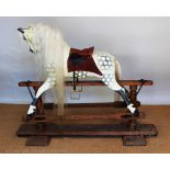 An Ayres type dappled rocking horse, with replacement leather saddle, on pine stand,