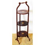 An Edwardian three-tier cake stand, the mahogany stand with shell inlaid detailing,