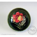 A Moorcroft lily pattern bowl, decorated with a single flower against a mottled blue - green ground,