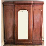 A Victorian mahogany breakfront wardrobe, with arched mirrored door flanked by two panelled doors,