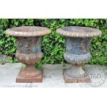 A pair of Victorian style cast iroin garden urns, decorated with putto, on square bases,