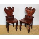 A pair of Victorian carved mahogany hall chairs, with shield shaped backs and solid seats,