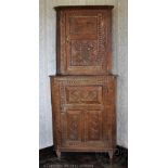 A Welsh oak two section corner cabinet, the top with panelled door enclosing serpentine shelves,