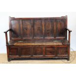 A George III Welsh oak settle, with five panelled back, hinged seat on stile legs,