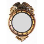 A 19th century Regency style gilt wood and gesso circular convex wall mirror, with eagle surmount,