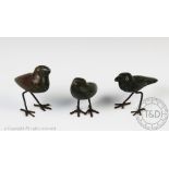 Three carved soapstone models of naive birds, each modelled standing on iron legs,