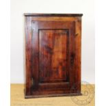 A George III oak hanging cabinet, with panelled door enclosing shelves,