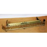 An Edwardian brass fender, of pierced quatrefoil form on bun feet, 155cm with a further fender,