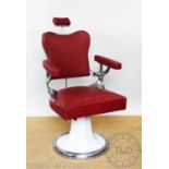 A vintage barbers chair, possibly 1950's, with chrome frame and red leatherette upholstery,