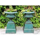 A pair of Victorian style green painted cast iron garden urns on stands,