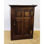 An 18th century oak cupboard, with panelled door, enclosing shelves and drawers,