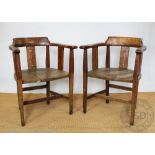 A pair of Arts and Crafts oak tub chairs, with curved backs and solid seats, on tapered legs,