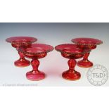 Four 19th century gilt cranberry glass comports, with shaped rims, on circular bases,