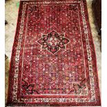 A Turkish hand woven wool carpet, decorated with a central medallion against a foliate red ground,