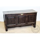 An early 18th century oak coffer, with triple panelled front on stile legs,