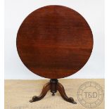 A George III oak tilt top table, the circular top on turned column and tripod base, hipped legs,