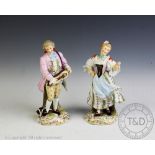 A pair of late 19th century German porcelain figures of a male hurdy-gurdy player and a female