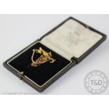 A hunting pin/clip, designed as a running fox against a riding crop, stamped '15ct',