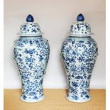 A large pair of Chinese blue and white floor vases and covers, decorated throughout with flowers,