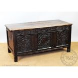 An 18th century oak coffer, with carved and panelled front, on stile legs,