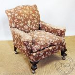 An early 20th century caved mahogany club type library chair, with floral upholstery,