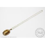 A 9ct gold pendant and chain, London 1974, designed as an oval hardstone panel,
