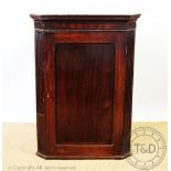 A George III mahogany corner cabinet, with panelled door and fluted sides,