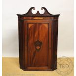 A George III inlaid mahogany corner cabinet, with swans neck pediment,