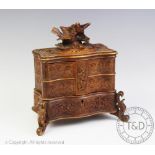 A Black Forest type carved wood jewellery box, of serpentine form and surmounted by two birds,