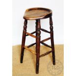 A late 19th century vernacular beech stool, with dished and shaped seat, on turned legs,