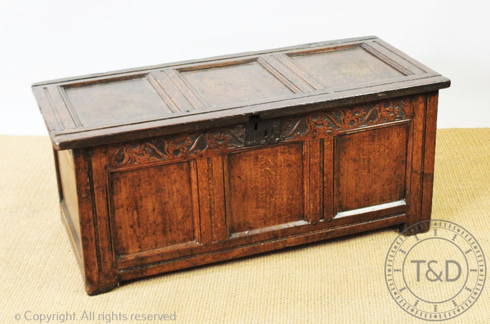 An 18th century oak coffer, with panelled sides and font, on stile feet,