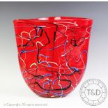 A contemporary studio glass vase, with trailed slip decoration against a red glass body,