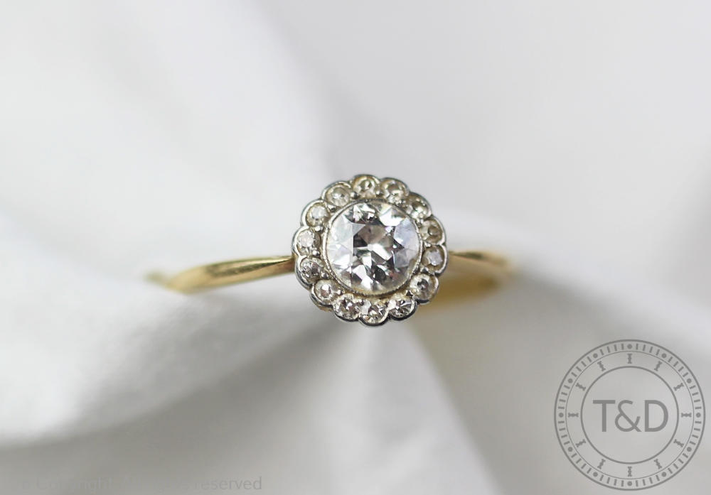 A diamond set daisy cluster ring, the central old brilliant cut diamond,