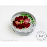 A Clichy Fantasy Flower paperweight, lampwork Carnelia blossom against a latticino ground,