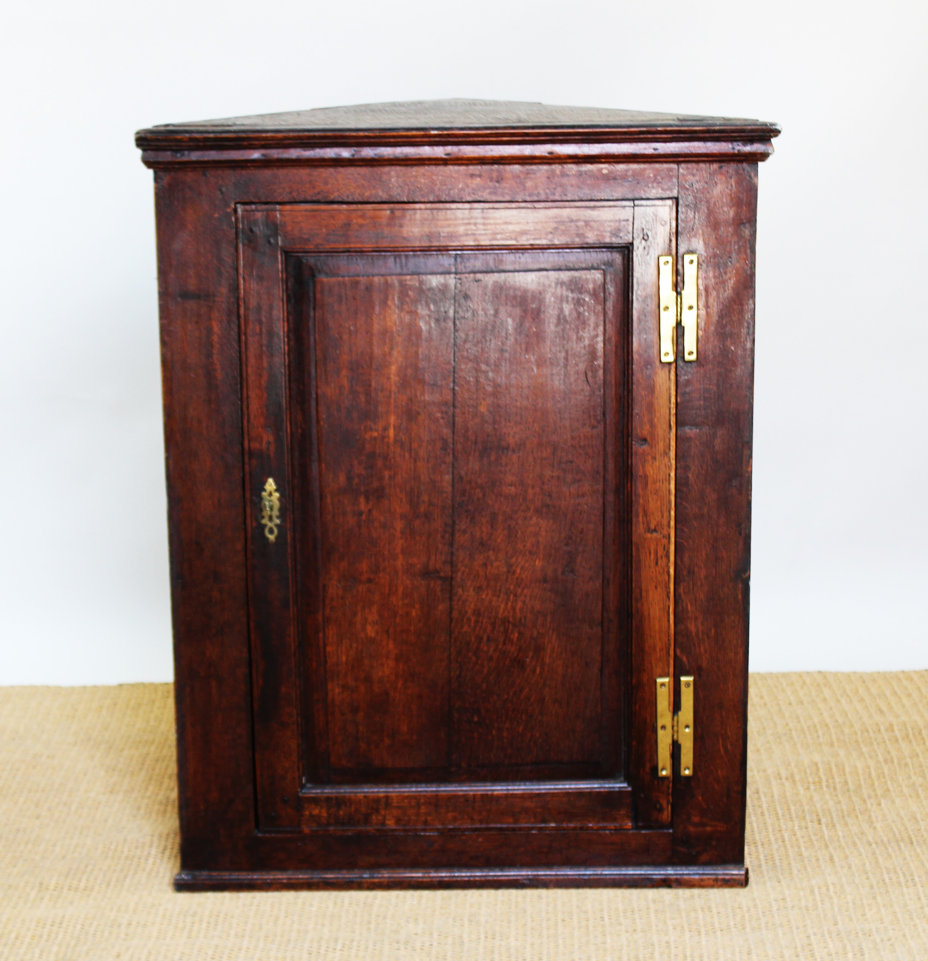 A George III oak hanging corner cabinet, with panelled door,