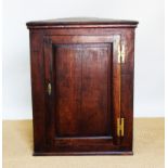 A George III oak hanging corner cabinet, with panelled door,