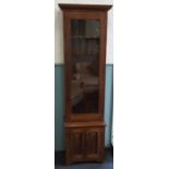 An oak gun cabinet, with glazed door and two cupboard doors beneath,