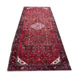 A Caucasian wool runner, worked with an all over floral design against a red ground