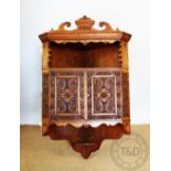 An Edwardian Arts and Crafts type carved oak corner cabinet, with open shelf and two cupboard doors,