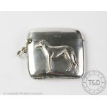 A silver vesta Henry Matthews, Birmingham 1911, of cushion form and depicting a greyhound in relief,