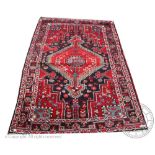 A Caucasian wool rug, decorated with a red geometric gull against a foliate ground,